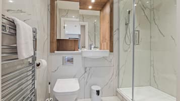 A modern bathroom with a glass shower enclosure, a toilet, and a sink.