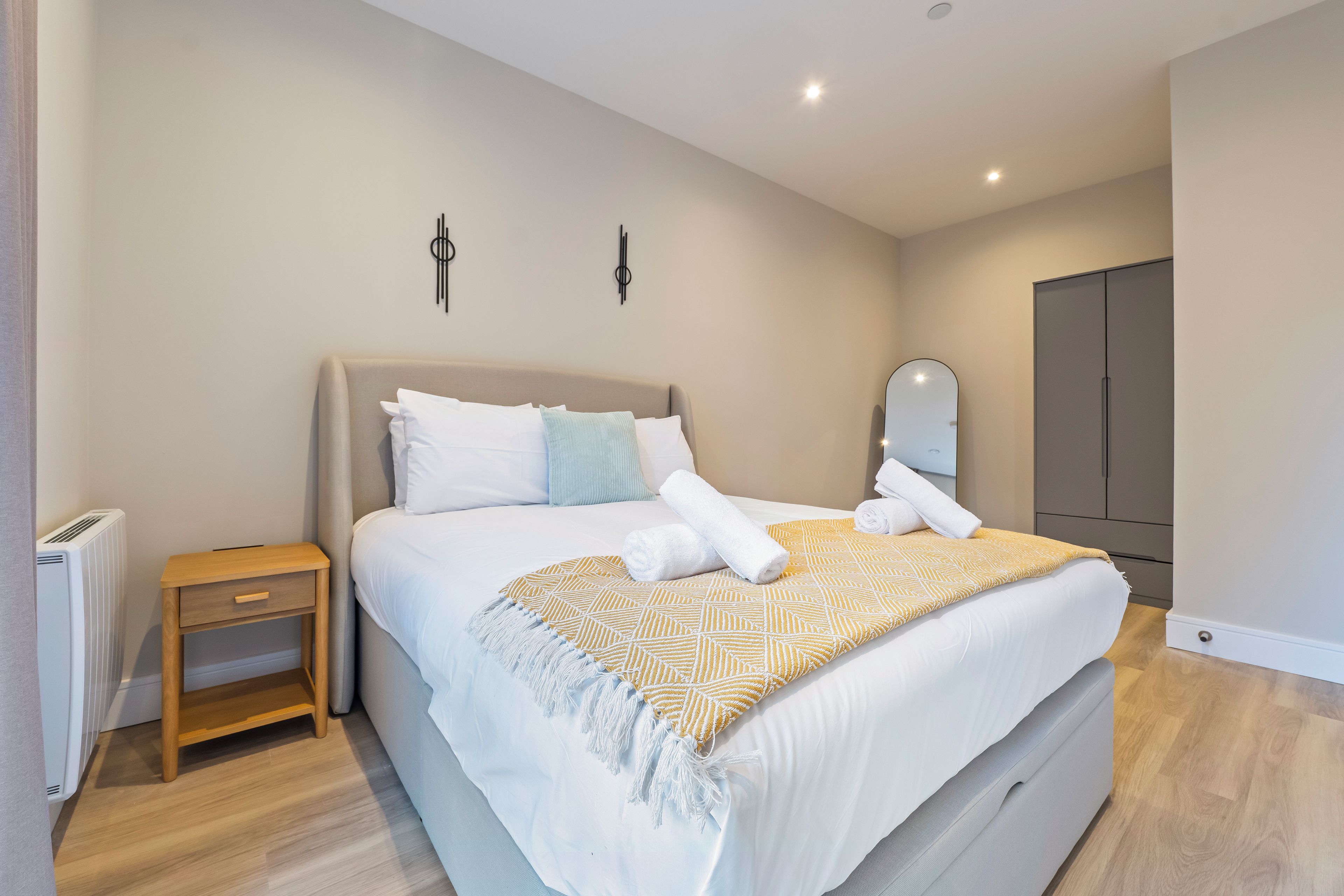 Une chambre moderne avec un grand lit, des tables de chevet, un radiateur et une armoire.