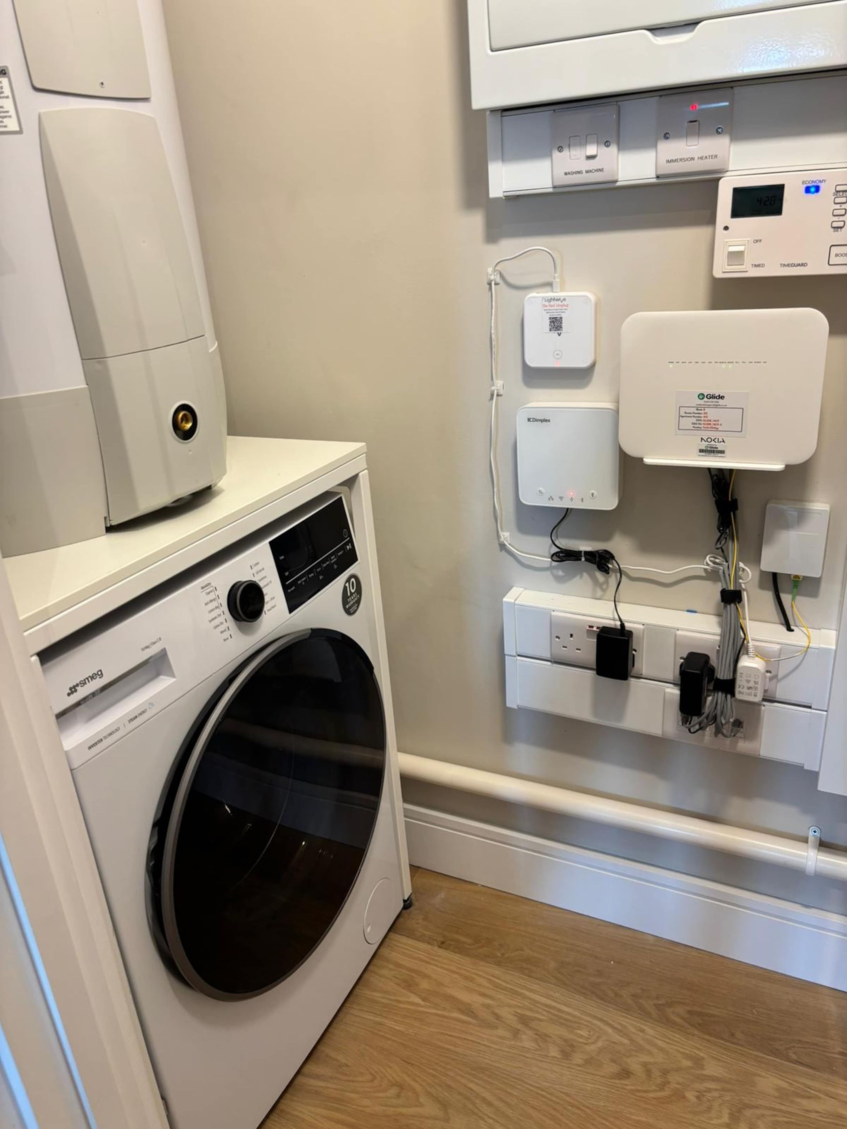 Un área de lavandería compacta con lavadora de carga frontal, secadora empotrada y panel de control con varias opciones.