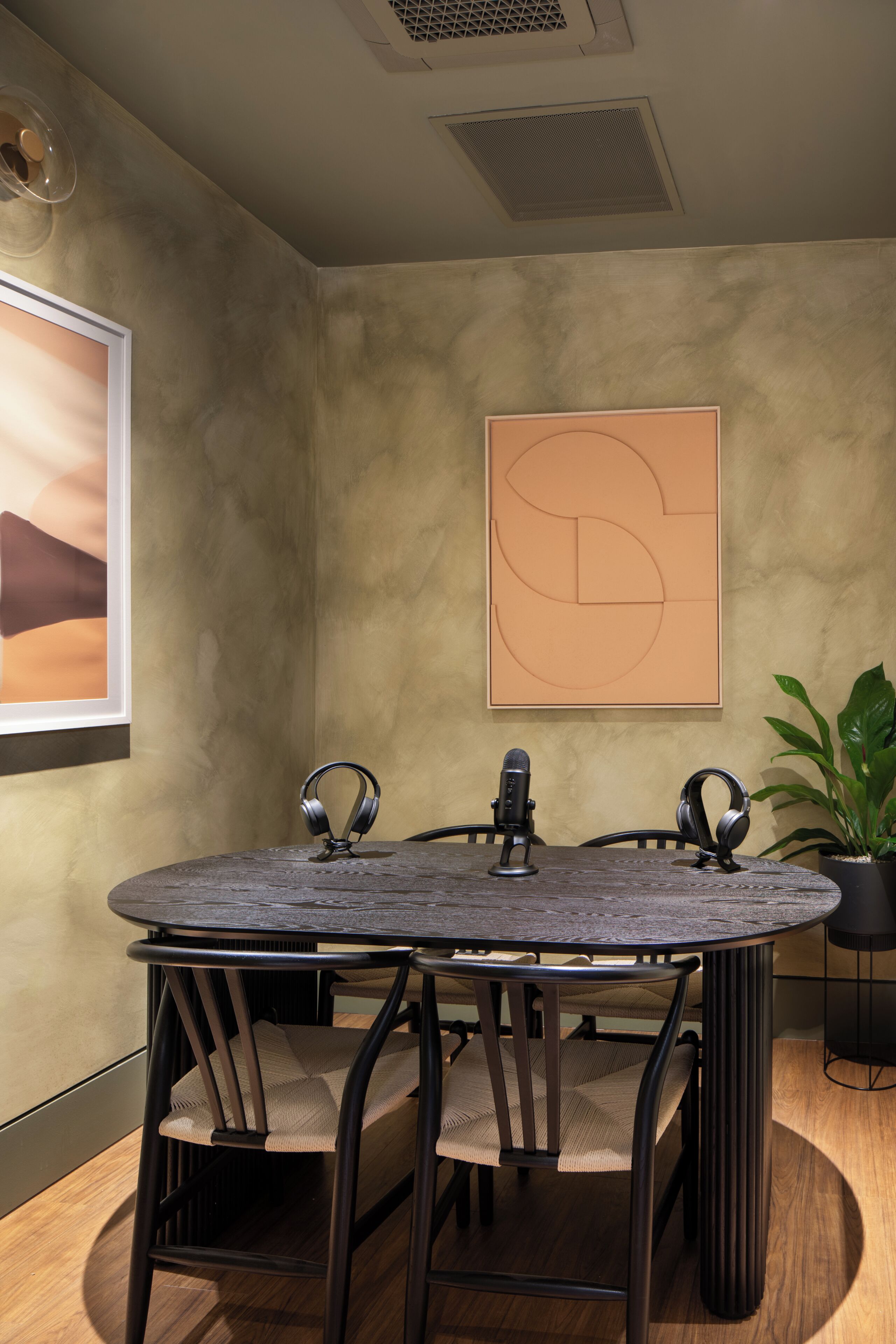 A conference room with a round table, two chairs, a microphone, and headphones.