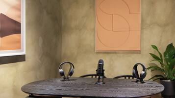 A conference room with a round table, two chairs, a microphone, and headphones.