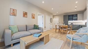 Una sala de estar moderna con sofá, mesa de centro y un comedor con sillas y mesa.