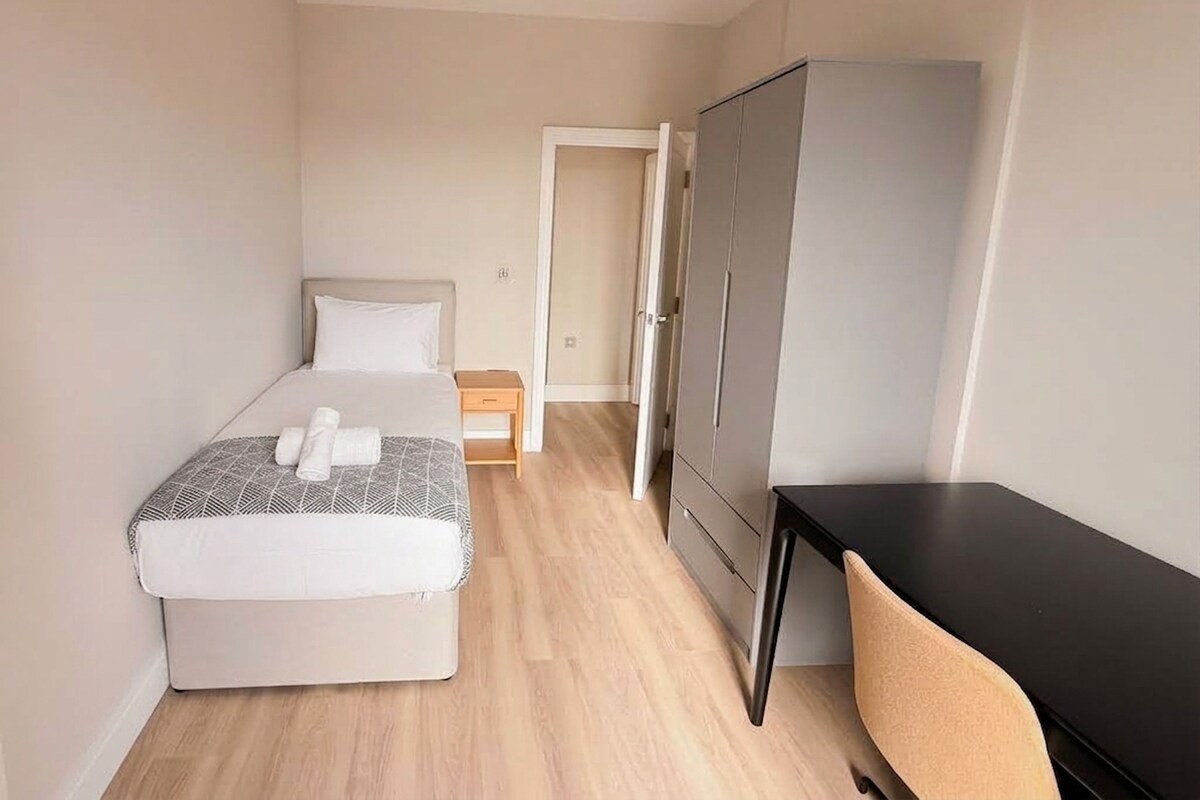 A bedroom with a bed, a desk, and a wardrobe.