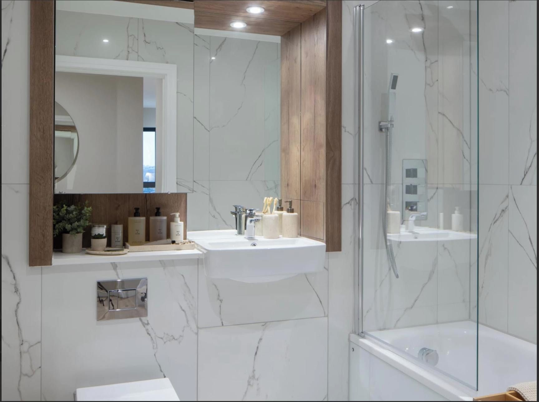 A modern bathroom with a marble wall, a wooden vanity, a glass shower enclosure, and a built-in sink.
