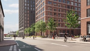 A modern urban street with high-rise buildings, a bike lane, and outdoor seating areas. - StayCozy Apartments in Birmingham (Birmingham)