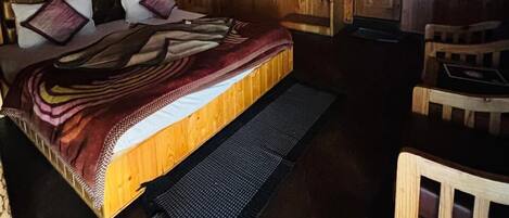 A wooden cabin bedroom with a bed, a small table, and a chair.