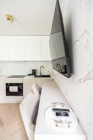 A modern kitchen with a built-in TV, a marble countertop, and a sleek design. - RentPlanet - Apartament Lanckorońska (Kraków)