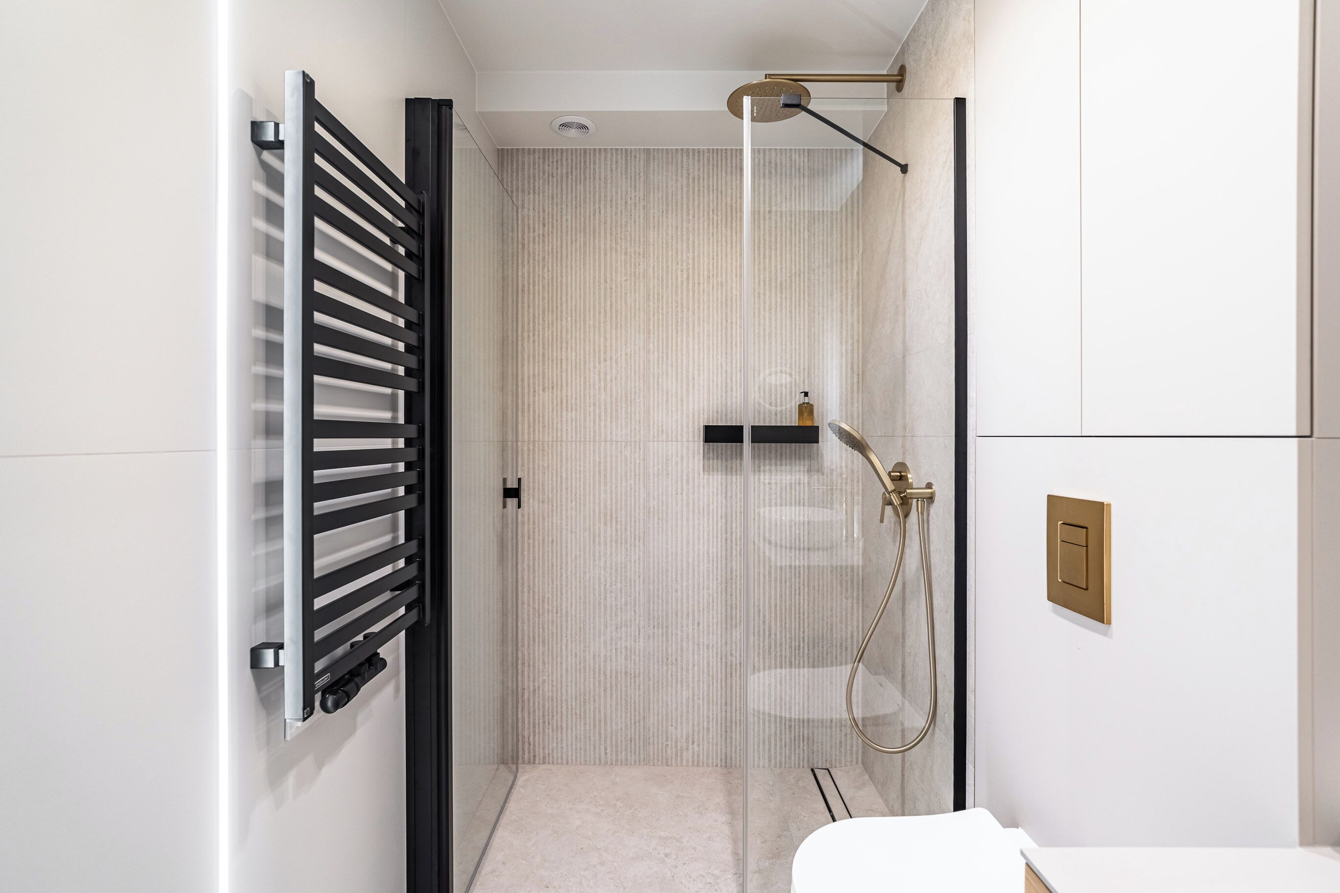 Une salle de bain moderne avec une douche à parois de verre, un porte-serviettes et des toilettes.