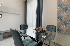 Ein moderner Essbereich mit einem Glastisch, blauen Stühlen und floralem Wandpapier.