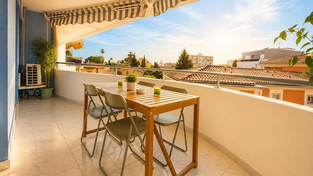 A balcony with a wooden table and chairs, a potted plant, and a view of the cityscape. - La Terrasse Bleue-Private covered parking 150 m from Juan Les Pins beach (Antibes)