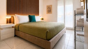 A modern bedroom with a bed, bedside tables, a wall-mounted light, a window with blinds, and a towel rack. - La Terrasse Bleue-Private covered parking 150 m from Juan Les Pins beach (Antibes)