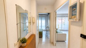 A hotel hallway with a wooden vanity, a mirror, a potted plant, a telephone, and a door leading to a room with a bed and a window. - La Terrasse Bleue-Private covered parking 150 m from Juan Les Pins beach (Antibes)