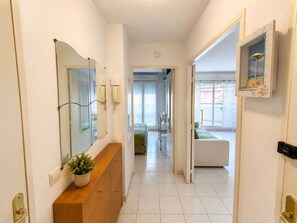 A hotel hallway with a wooden vanity, a mirror, a potted plant, a telephone, and a door leading to a room with a bed and a window. - La Terrasse Bleue-Private covered parking 150 m from Juan Les Pins beach (Antibes)