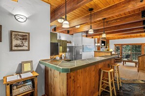 Eine Bar mit Holzboden, Hockern, einem Kühlschrank und einem großen Fenster.