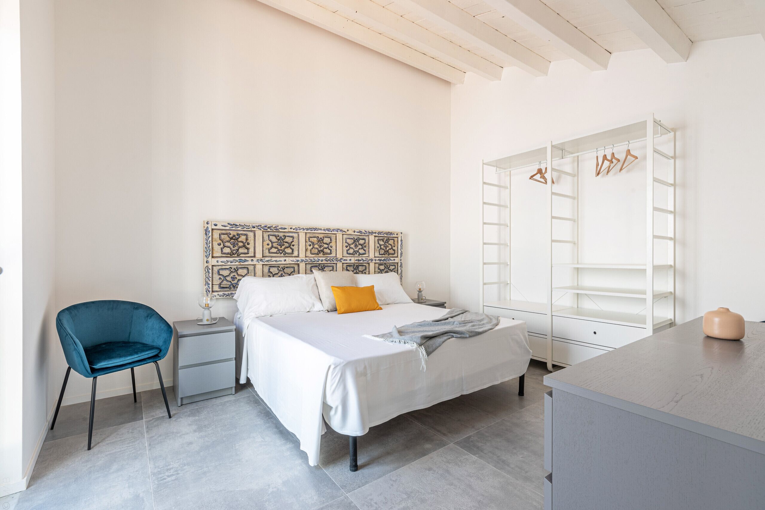 A bedroom with a bed, a chair, a nightstand, a dresser, and a wardrobe.