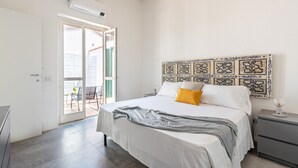 Un dormitorio con cama, una mesita de noche, un panel decorativo en la pared y un ventanal corredero que da a un área exterior.