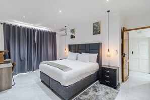 Ein modernes Schlafzimmer mit einem großen Bett, Nachttischen, einem Schreibtisch und einem Kleiderschrank.
