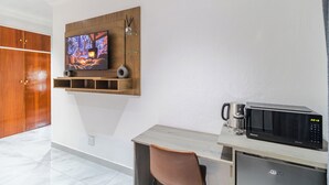 Una cocina moderna con microondas, cafetera y televisor de pantalla plana montado en un estante de madera.