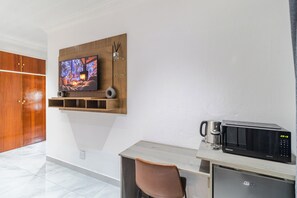 A modern kitchen with a microwave, coffee maker, and a flat-screen TV mounted on a wooden shelf. - Boutique Hotel-Style Room In Ferndale-D4 (Randburg)