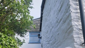 Un estrecho callejón con un edificio blanco, una puerta azul y una ventana pequeña.