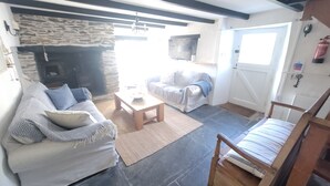 Una sala de estar con chimenea de piedra, un sofá, una mesa de centro y una silla de madera.