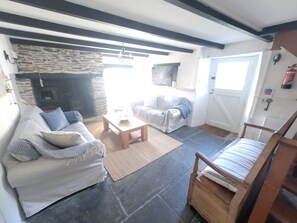 Un salon avec une cheminée en pierre, un canapé, une table basse et une chaise en bois.