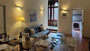 A dining area with a table set for four, a sofa, and a kitchen in the background. - Cosy apartment for 8 guests with WIFI, A/C, TV and balcony (Lucca)