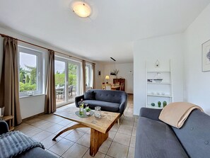 Ein Wohnzimmer mit einer Couch, einem Couchtisch, einem Essbereich mit Stühlen und einem Bücherregal.