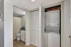 Ein Badezimmer mit Toilette, Duschvorhang und integrierter Waschmaschine.
