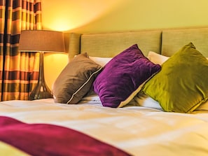 Ein Bett mit vielen Kissen, einer Lampe und Vorhängen.