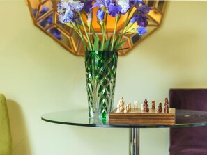 Ein Glastisch mit Schachbrett und Blumenvase.