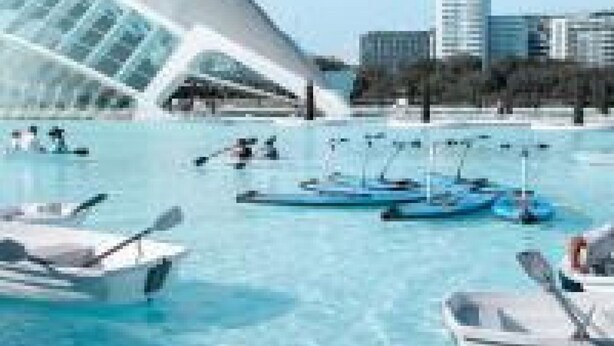 Een hotel aan het water, met een opvallend wit gebouw, boten en een helderblauwe lucht.