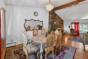 Une salle à manger avec une table ronde, des chaises décorées, un lustre et un mur en pierre.