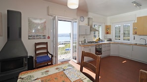 A kitchen with a stove, sink, and dining area with a view. - Villa Samanta in Gardone Riviera (Gardone Riviera)