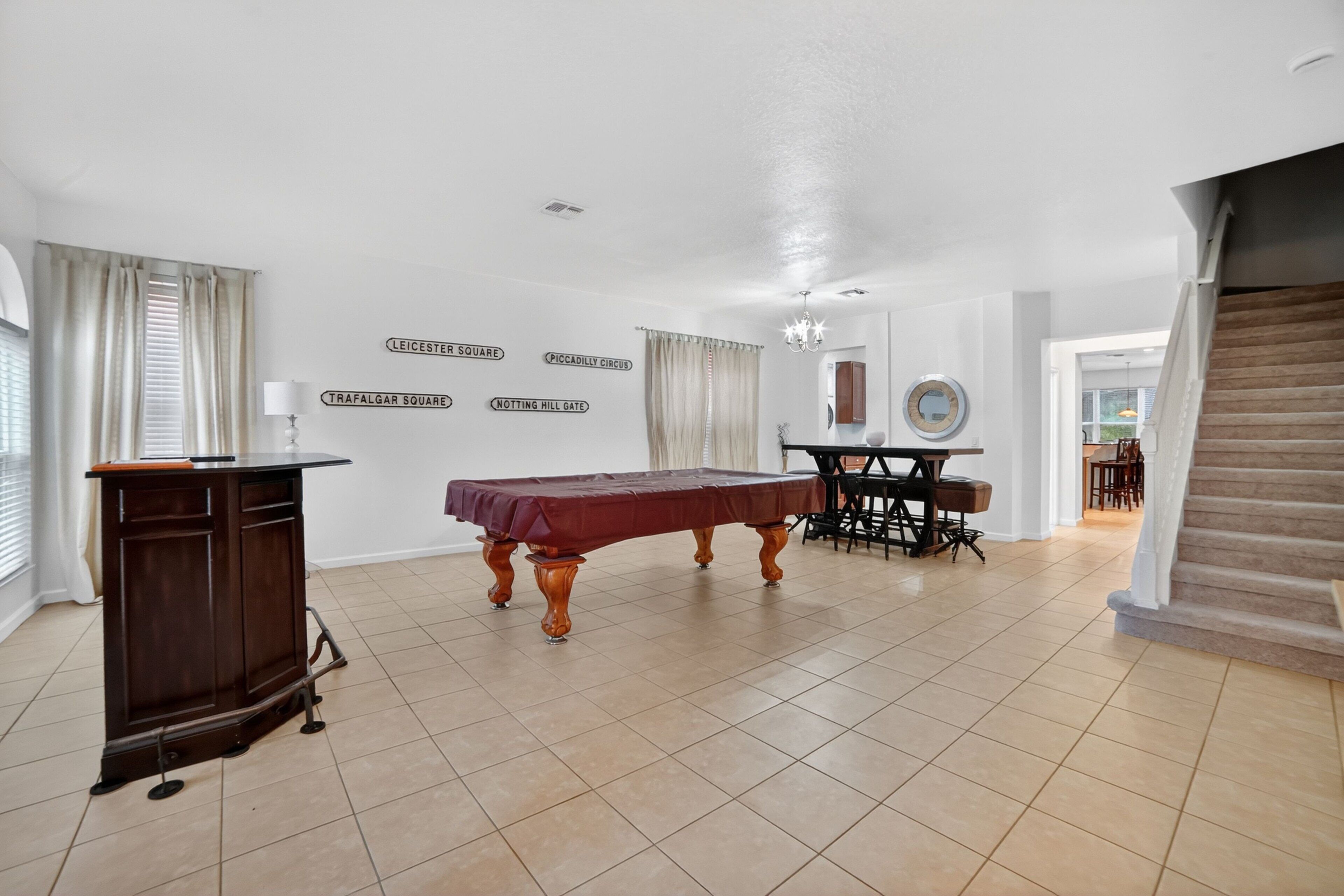 A spacious room with a billiards table, a small desk, and a mirror on the wall.