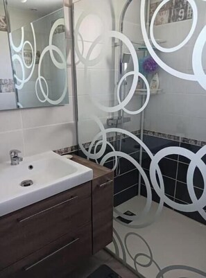 Une salle de bain avec un lavabo blanc, un meuble-lavabo en bois foncé et des motifs décoratifs sur les murs.