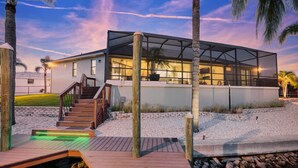 Ein modernes Haus mit überdachter Terrasse, einer Holztreppe und einem Poolbereich.