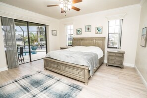 A bedroom with a large bed, a ceiling fan, a nightstand, a dresser, and a view of a pool. - Apollos Anchor - 926 Golf Island Dr 5 Bedroom Home (Apollo Beach)
