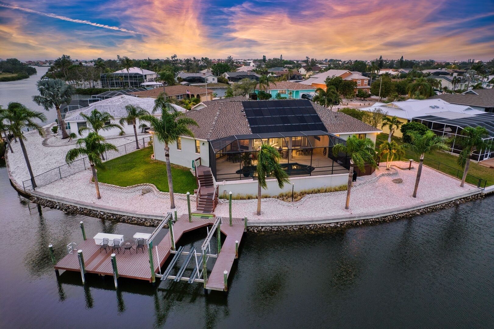 A waterfront property with a dock, a covered outdoor area, and solar panels.