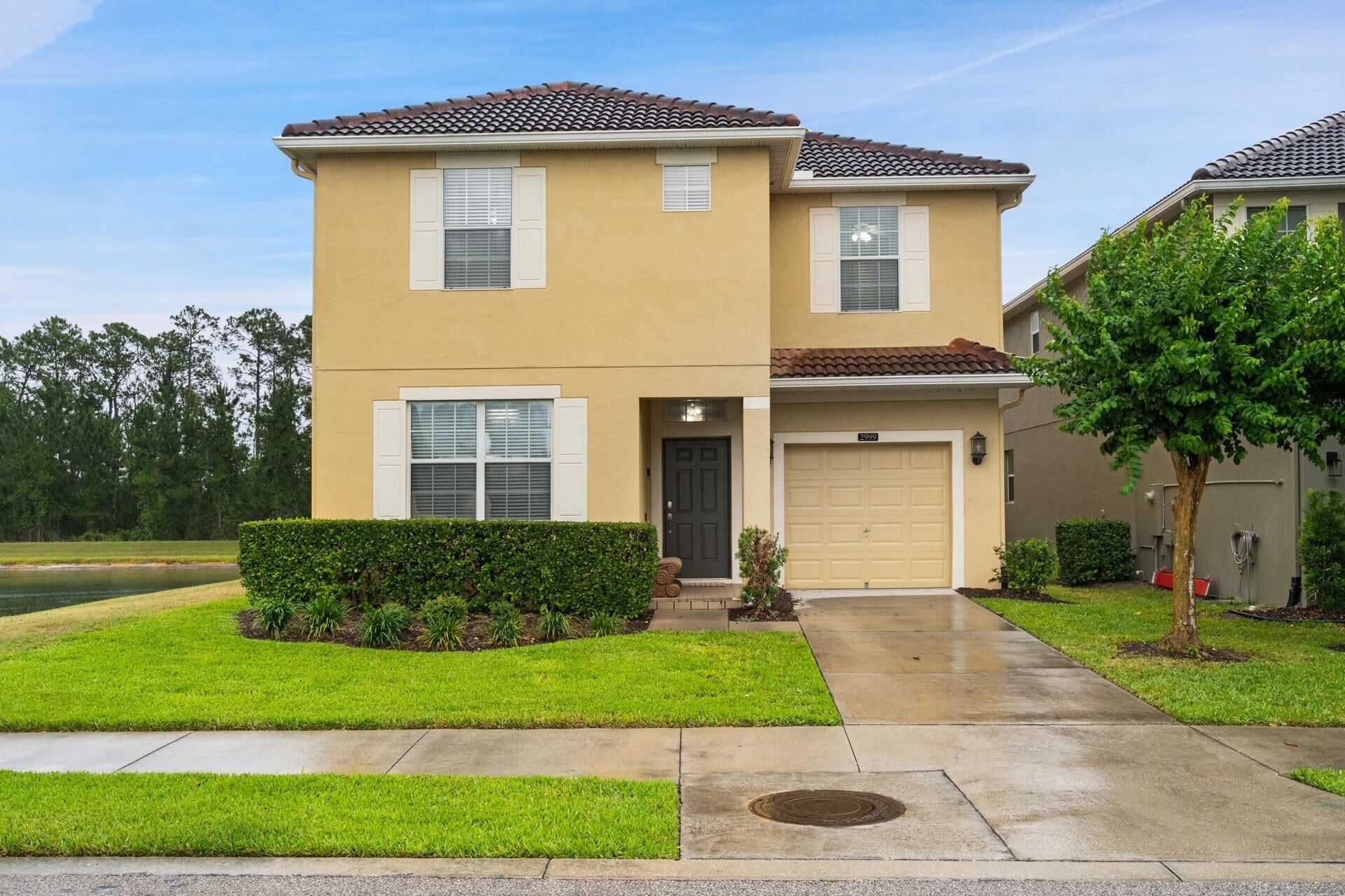 A two-story residential building with a beige exterior, a front garage, and a well-maintained lawn.