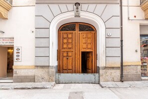 A double wooden door with a white archway, a small sign above the door, and a number '6' on the wall to the right. - Ballar Duplex With Terrace by Wonderful Italy (Palermo)
