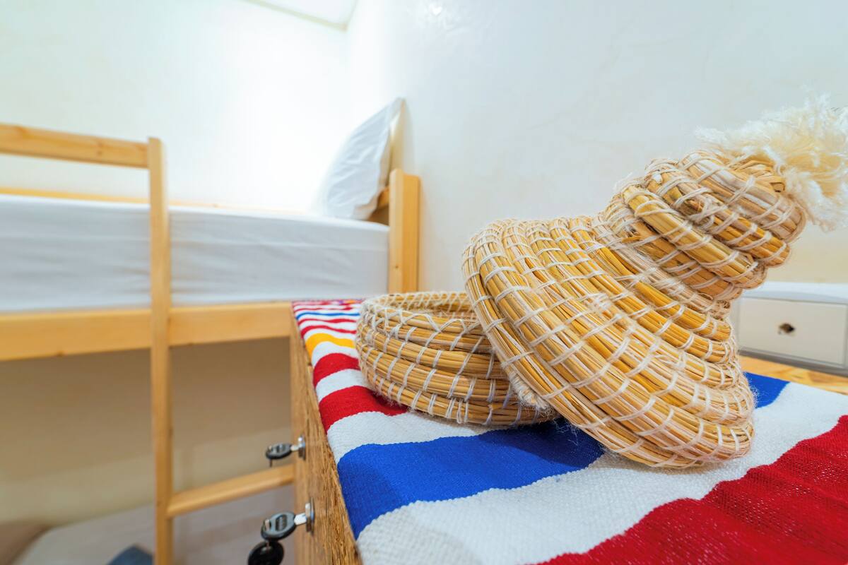 A bunk bed with a striped blanket, a wicker basket, and a white pillow.