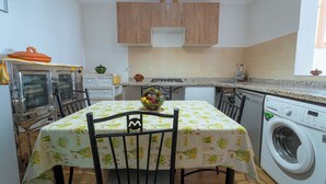 A compact kitchen with a table, chairs, a washing machine, and a microwave.