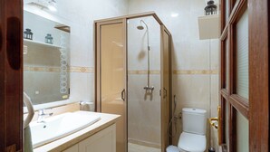 A bathroom with a glass-enclosed shower, a sink, and a toilet.