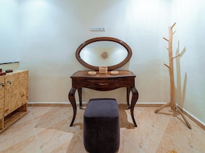 A wooden vanity with a mirror, a bench, and a coat rack in a room with tiled flooring. - Roots Surf House (Agadir)