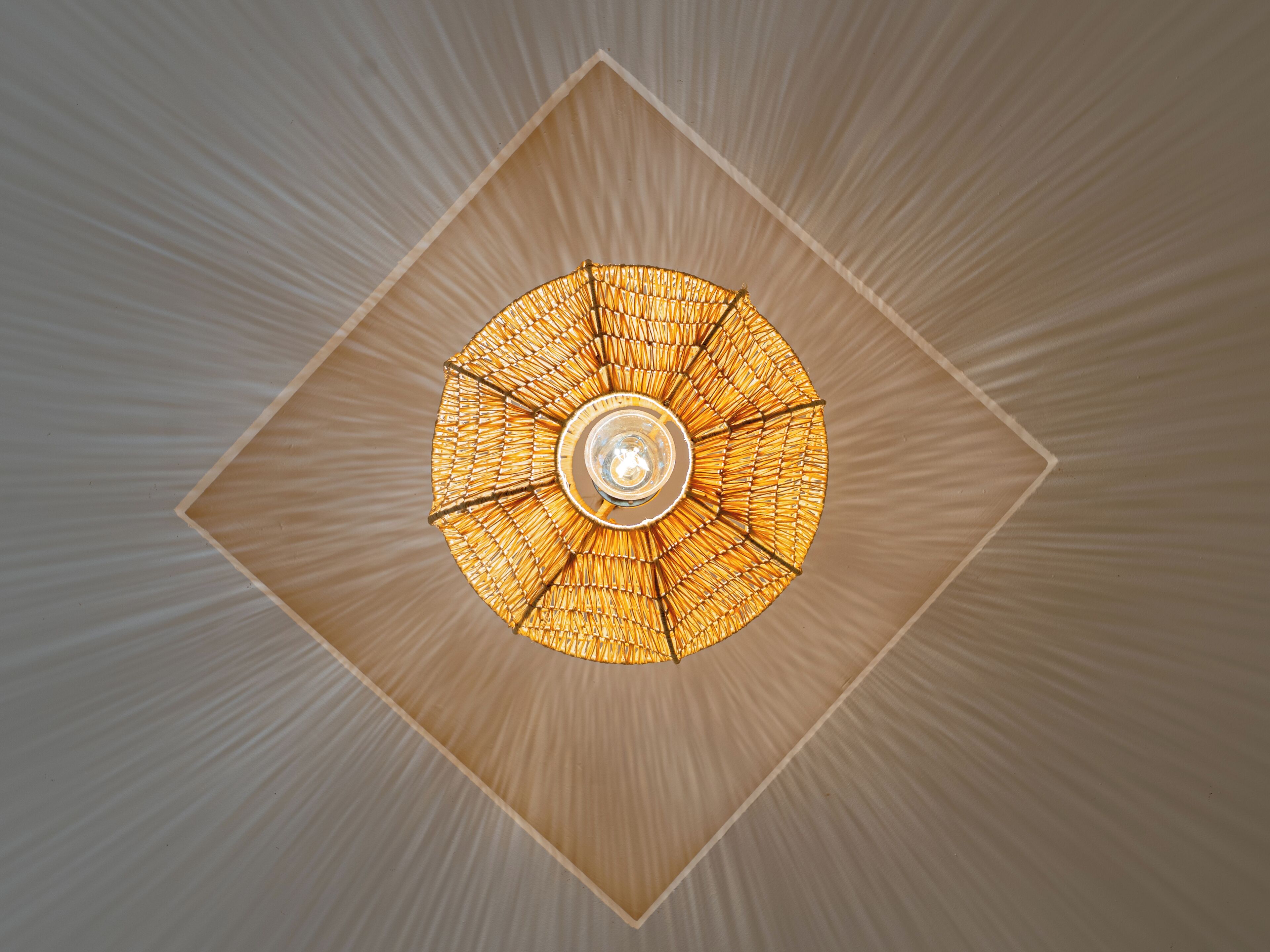 A ceiling with a circular, woven light fixture.