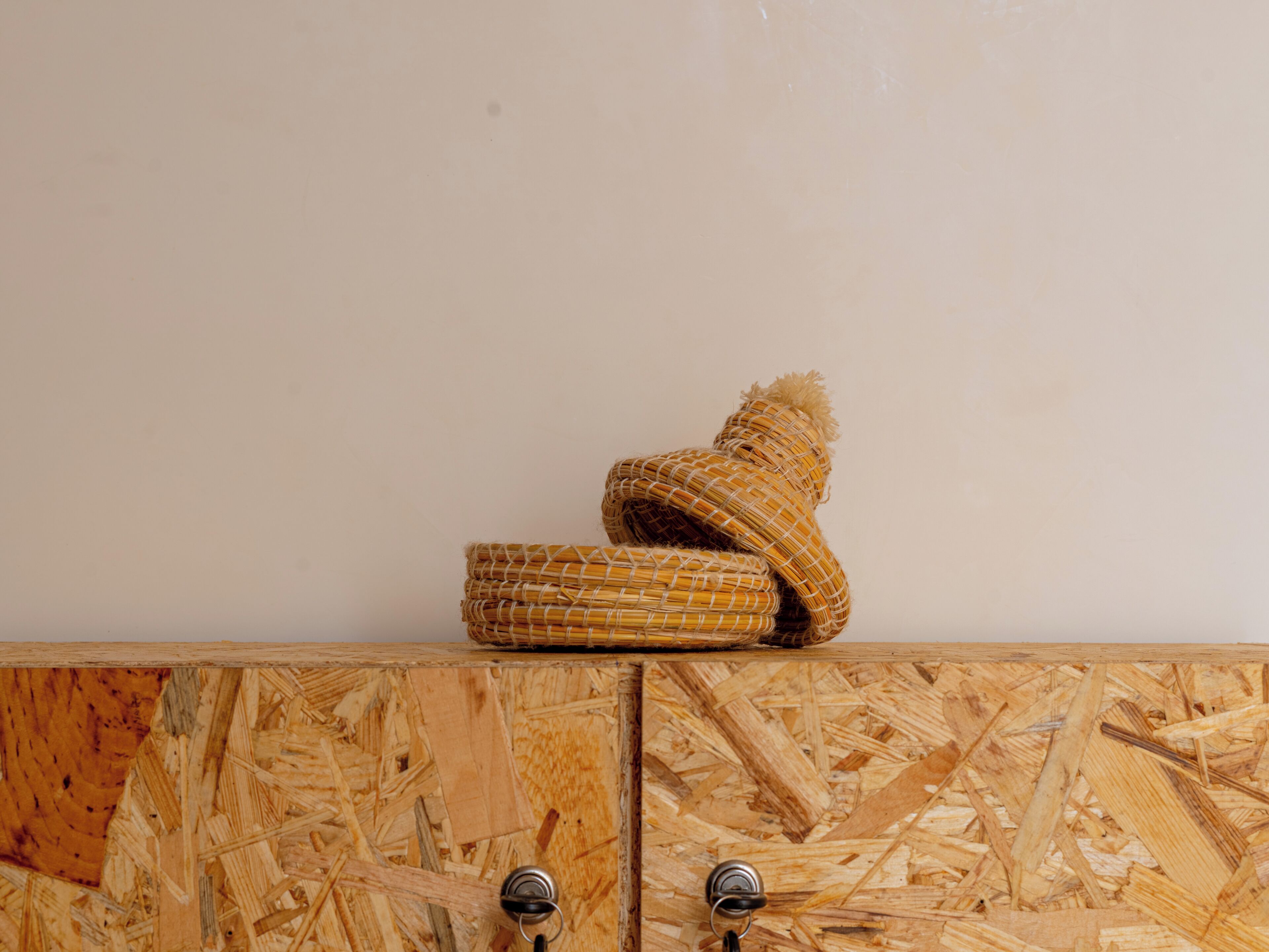 A woven basket on a wooden cabinet with two metal handles.