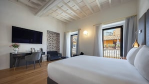 A hotel room with a bed, desk, chair, TV, and balcony with outdoor furniture. - Ara di Marte Living Art (Rome)