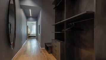 Un pasillo moderno con suelo de madera, un espejo grande y un vestidor con estantes y cajones.