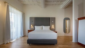 A large bed with a dark headboard, two bedside tables with lamps, a large mirror, and a wooden floor. - Ara di Marte Living Art (Rome)